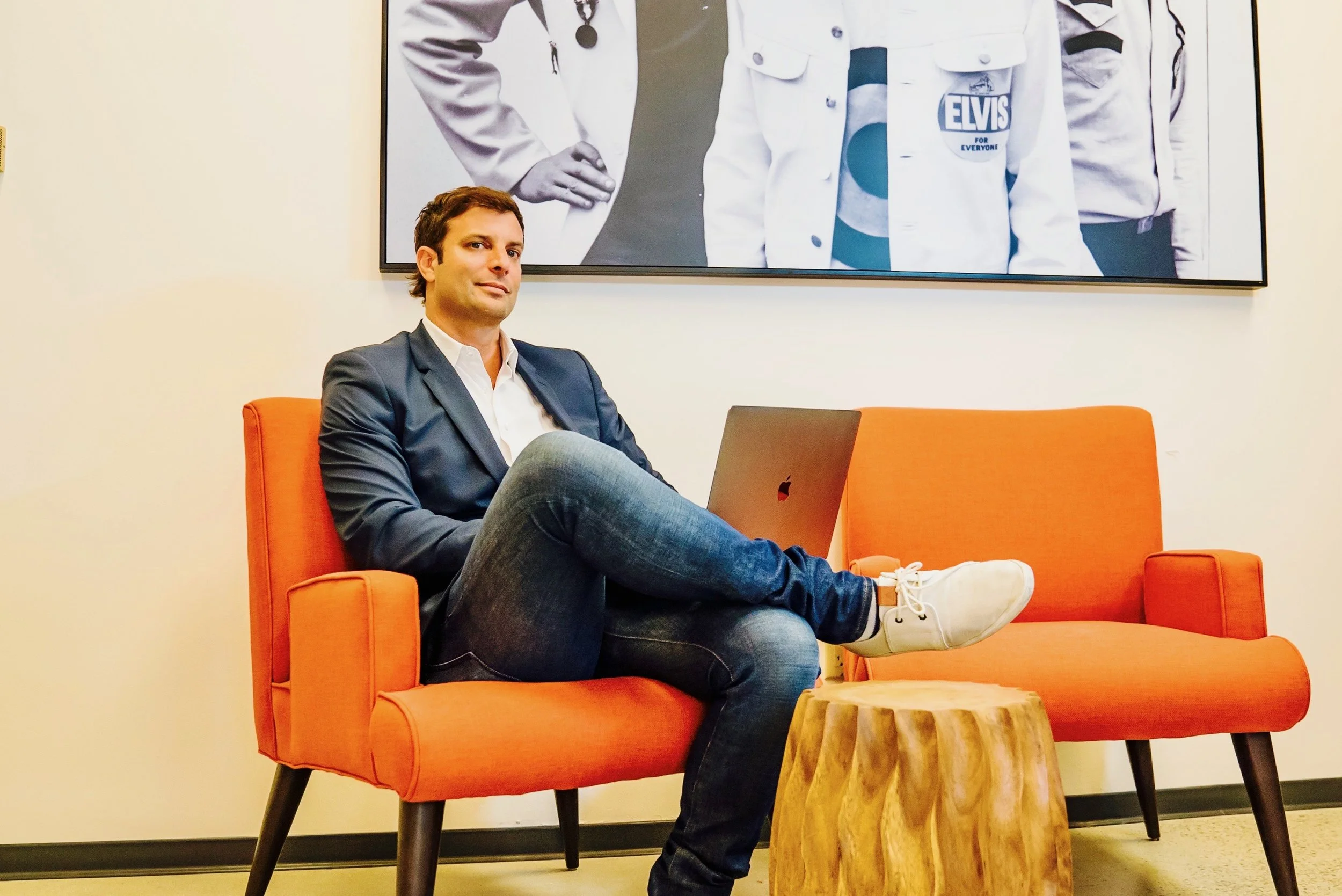 Founder seated in an orange armchair with a laptop